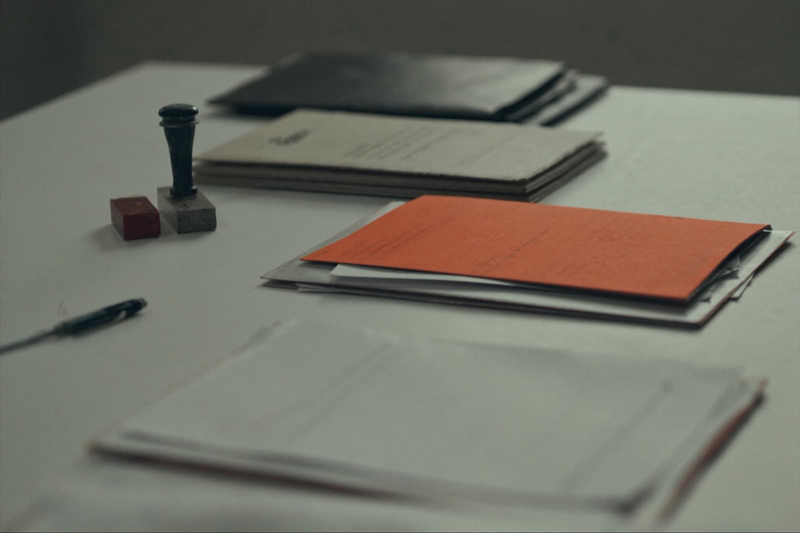 Export documentation on a desk — document wallets, an orange folder, a rubber stamp and a pen