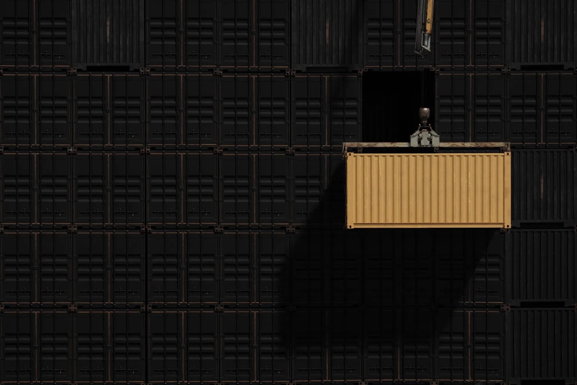 A gold shipping container suspended from a crane spreader against a wall of stacked black containers
